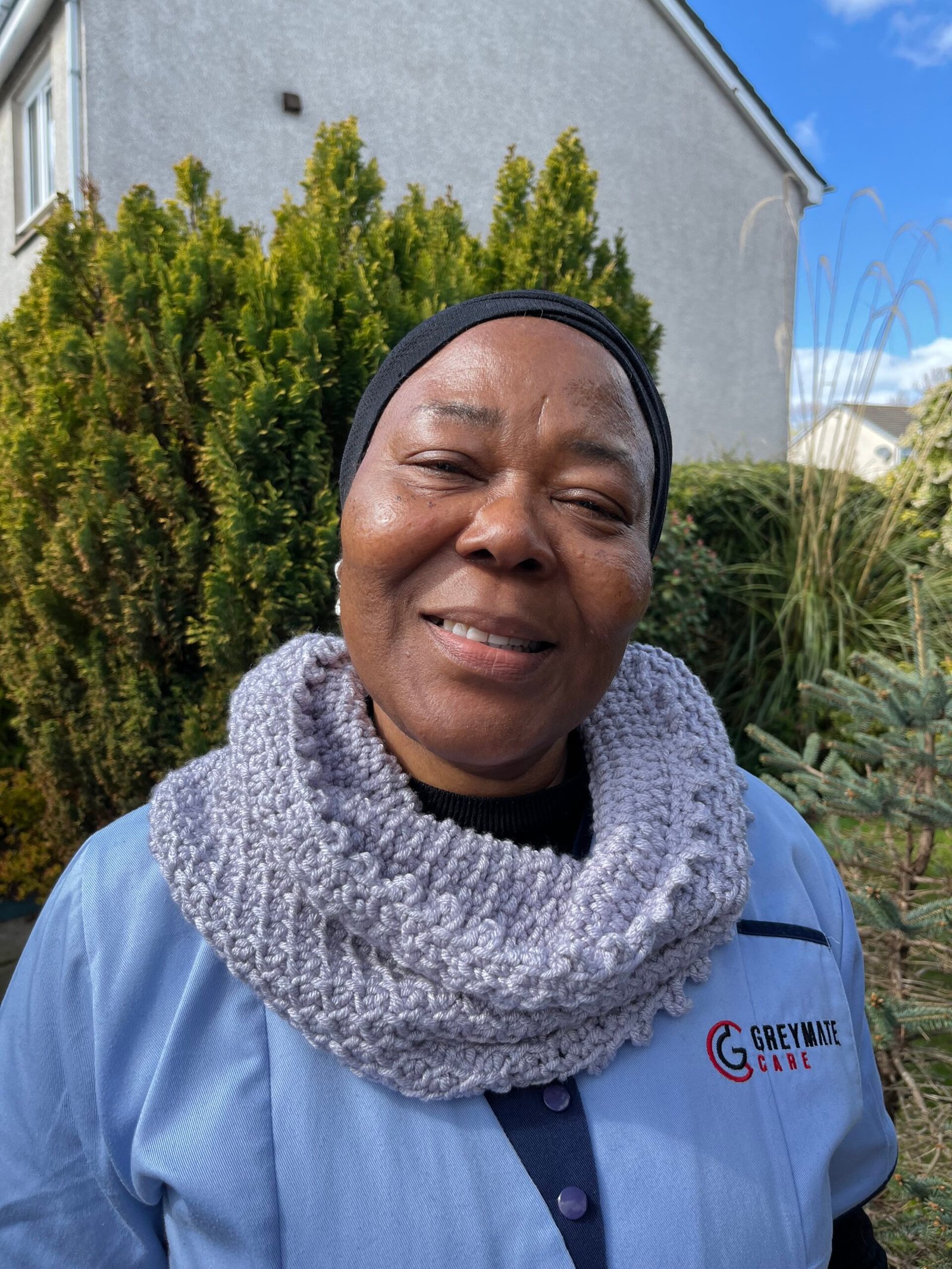 A woman wearing a crocheted grey cowl.